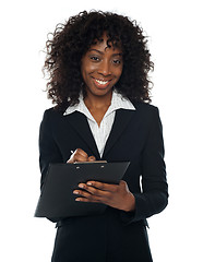 Image showing Pretty corporate woman writing on clipboard