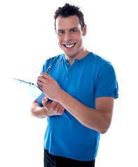 Image showing Smiling man writing on clipboard