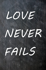 Image showing Love Never Fails written on a smudged chalkboard