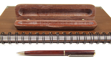 Image showing pen in an opened wooden case on notebook