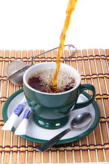 Image showing Pouring fresh tea into green cup