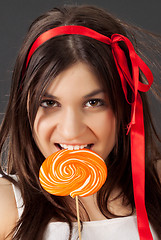 Image showing Beautiful girl bites lollipop
