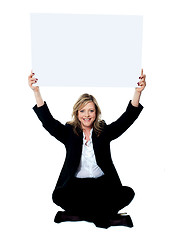 Image showing Seated female employee holding white clipboard over her head