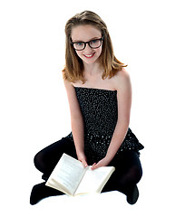 Image showing School girl sitting on floor holding book