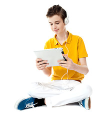 Image showing Seated boy watching video on tablet