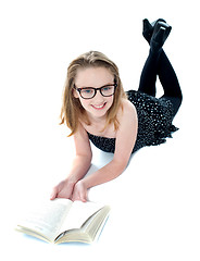 Image showing Smiling little girl lying with an open book