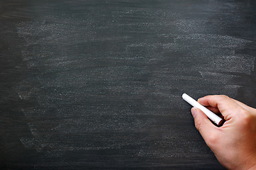 Image showing Smudged blackboard background with a hand holding chalk writing.