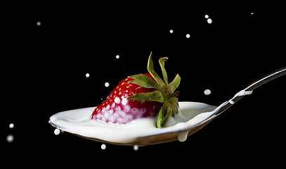 Image showing red, ripe strawberry falling in spoon with milk