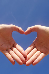 Image showing Man hands forming a heart over the blue sky 