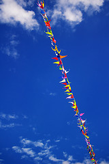 Image showing Multi colored party flags on a line on a background of blue sky 