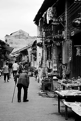 Image showing An old woman walking along the street