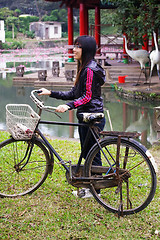 Image showing Asian woman riding bicycle with smile