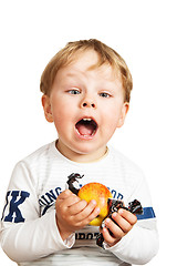 Image showing The little boy with an apple and sweets