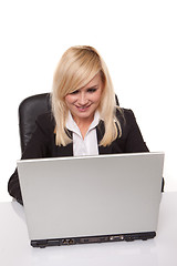 Image showing Efficient blonde businesswoman working on her laptop with her spectacles on the table alongside her