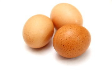 Image showing Three eggs lying down on a white linen background