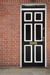 Image showing Black and White Door With a Brick Wall