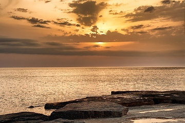 Image showing Sun going down over  water glowing on the shore