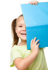 Image showing Cute little girl is hiding behind a book