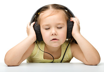 Image showing Cute little girl enjoying music using headphones