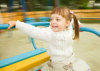 Image showing Cute little girl is riding merry-go-round