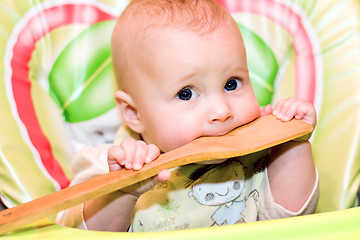 Image showing baby biting a wooden spoon
