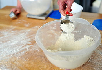 Image showing Female hand collecting flour from bowl