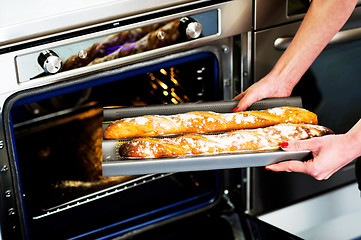 Image showing Hands of a woman holding hot baguette