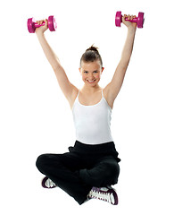 Image showing Smiling fit girl working out with dumbbells