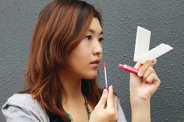 Image showing Asian woman doing make-up