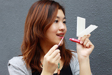 Image showing Asian woman doing make-up