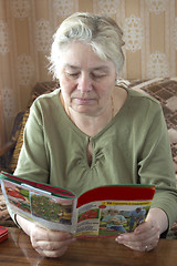 Image showing An elderly woman reading a magazine