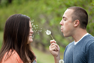 Image showing Young Couple Blowing Dandelions