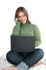 Image showing woman talking on mobile phone in front of laptop 