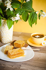 Image showing Honeycomb with a cup of tea and a bouquet of blooming Jasmine