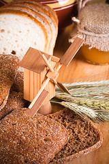 Image showing sliced bread and wheat on the wooden table 