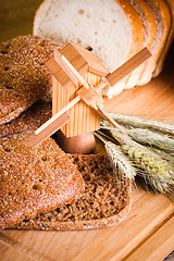 Image showing sliced bread and wheat on the wooden table 