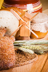 Image showing sliced bread and wheat on the wooden table 