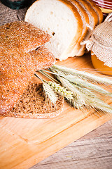 Image showing sliced bread and wheat on the wooden table 