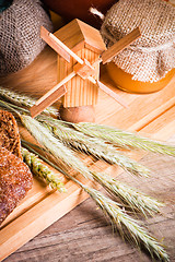 Image showing sliced bread and wheat on the wooden table 