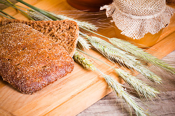 Image showing sliced bread and wheat on the wooden table 