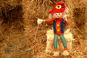 Image showing Straw doll sitting on hay bale