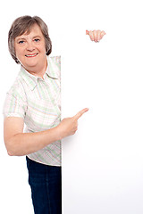 Image showing Causal senior lady pointing towards placard