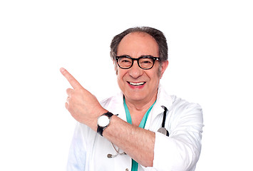 Image showing Mature doctor pointing upwards and away