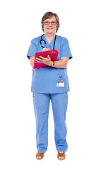 Image showing Senior female doctor writing on clipboard