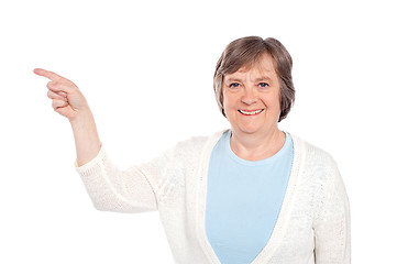 Image showing Matured casual lady pointing at copy space