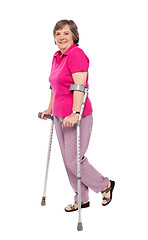 Image showing Smiling senior woman walking with crutches