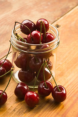 Image showing Cherry in glass jar isolated on the wooden background