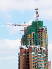 Image showing Building crane and building under construction against blue sky 