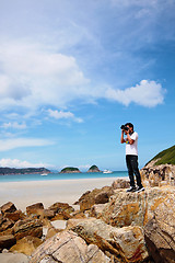 Image showing Portrait of a young man standing on a beach with a camera 