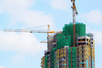 Image showing Building crane and building under construction against blue sky 